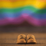 Zapatos de mexicanos frente a una bandera LGBT que simboliza la imposición ideológica sobre la familia y la educación