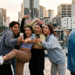 Grupo de jóvenes posando exageradamente para redes sociales mientras un joven camina en sentido contrario.